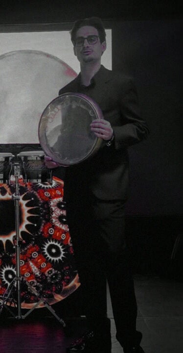 ALAN holding a doira on stage